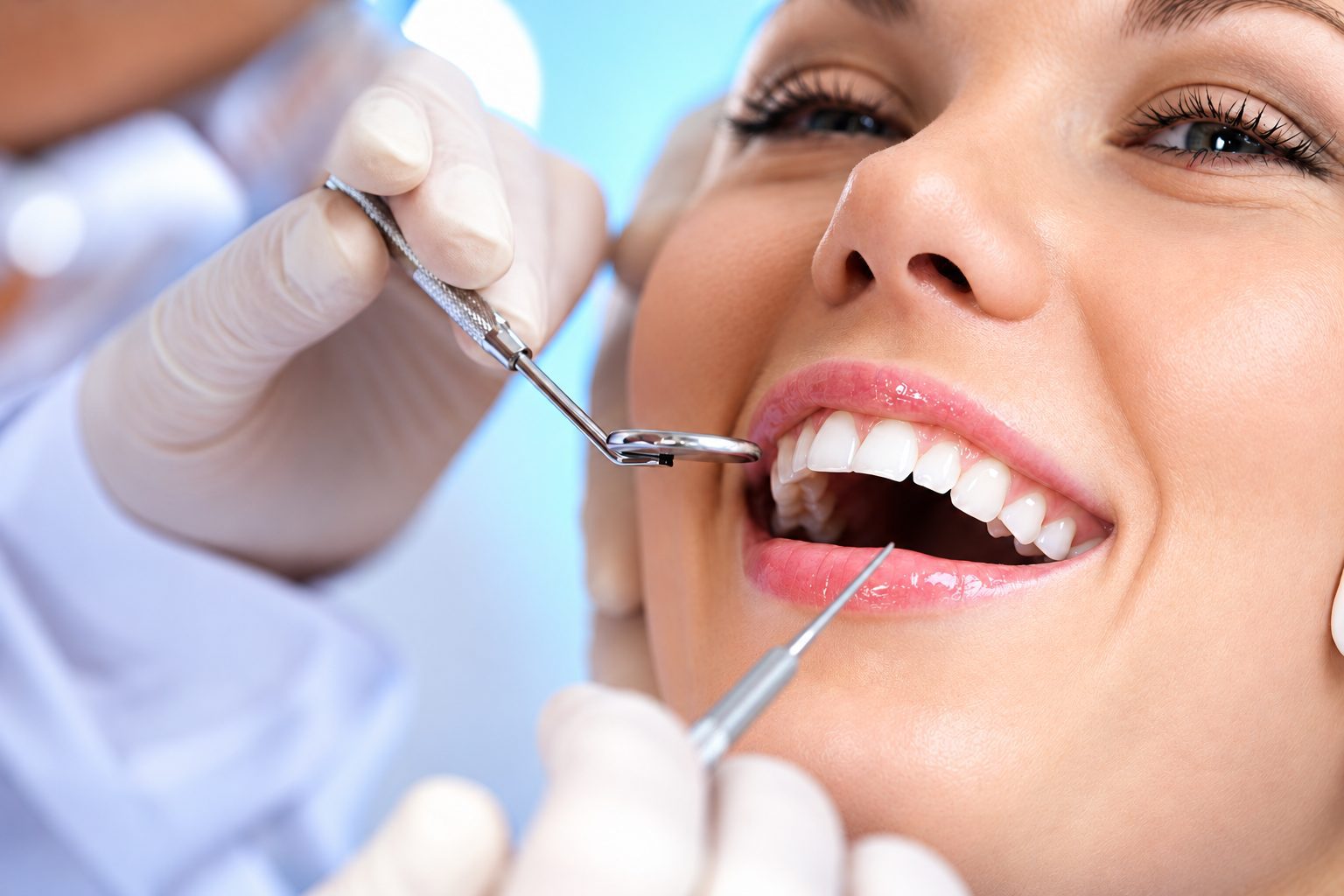 Người phụ nữ mỉm cười khi được kiểm tra răng bằng gương nha khoa